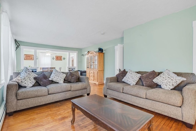 living area with a baseboard heating unit and wood-type flooring