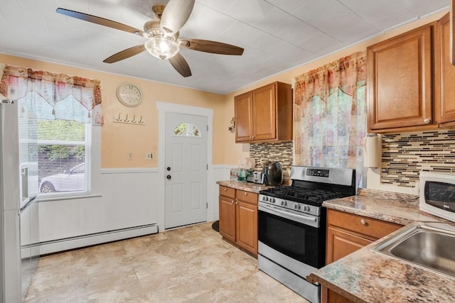 kitchen with stainless steel range with gas cooktop, brown cabinets, white microwave, and a baseboard heating unit