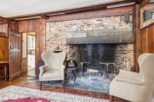 living area with wooden walls, hardwood / wood-style floors, and beam ceiling