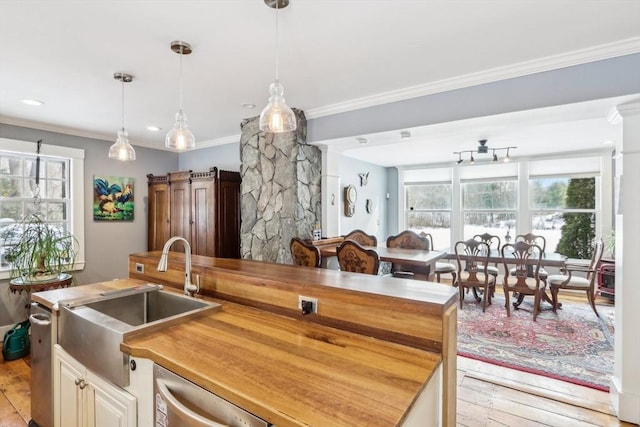 kitchen featuring ornamental molding, a barn door, wooden counters, and light wood-type flooring