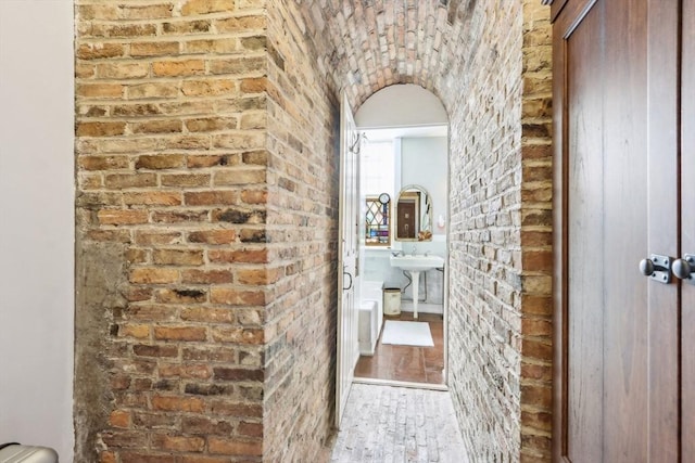 hall with brick wall, sink, and hardwood / wood-style floors