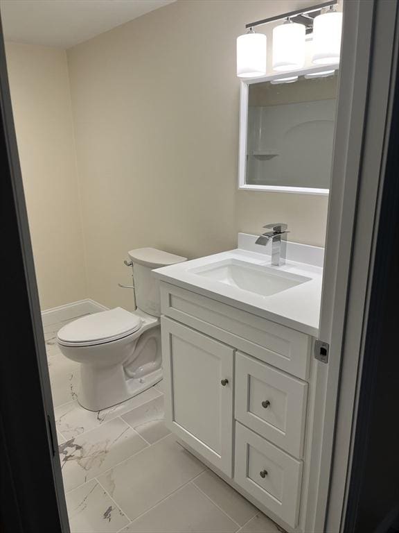 half bathroom with toilet, marble finish floor, and vanity