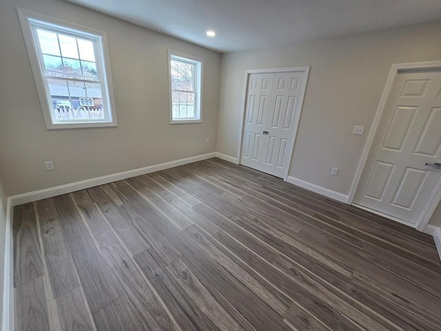 unfurnished bedroom featuring baseboards, dark wood finished floors, and a closet