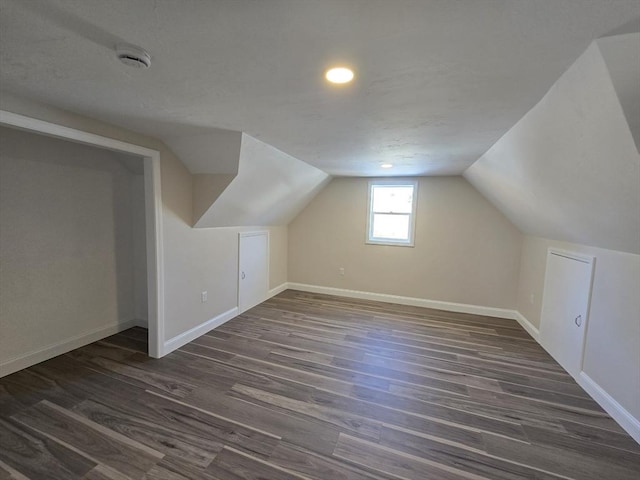 bonus room featuring dark wood-style floors, vaulted ceiling, and baseboards