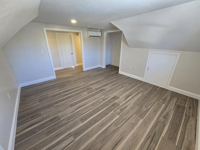 bonus room featuring lofted ceiling, baseboards, wood finished floors, and a wall mounted AC