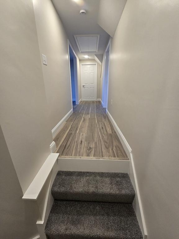 stairs featuring wood finished floors, attic access, and baseboards