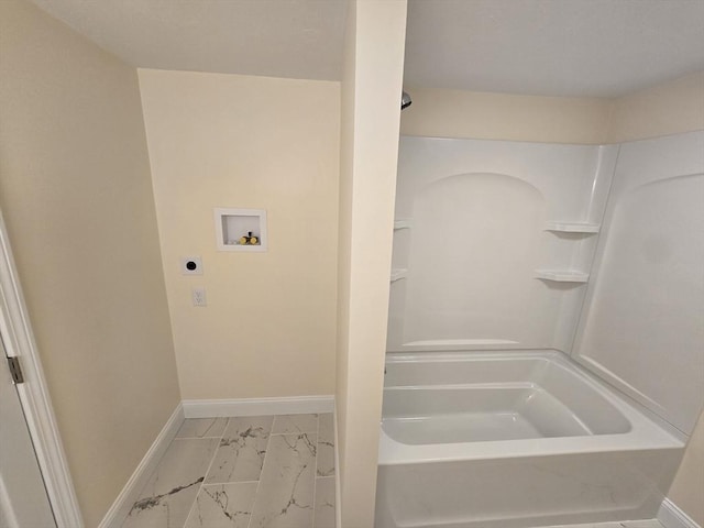 bathroom with washtub / shower combination, marble finish floor, and baseboards