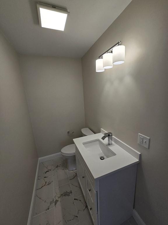 bathroom featuring marble finish floor, baseboards, vanity, and toilet