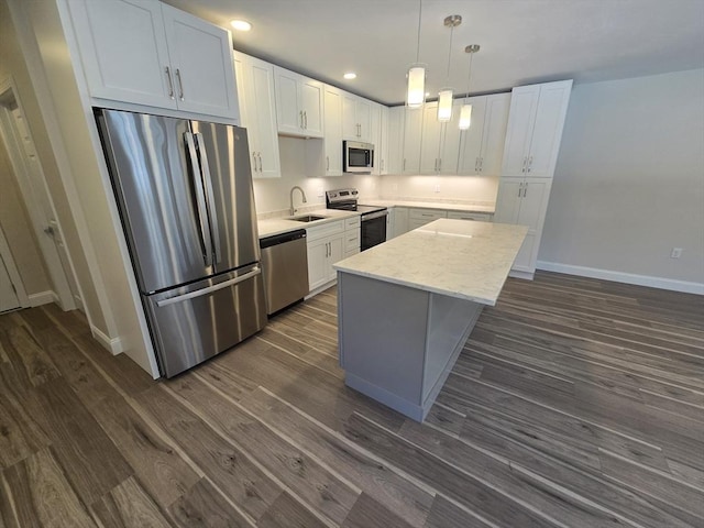 kitchen with stainless steel appliances, a sink, white cabinetry, a center island, and dark wood-style floors