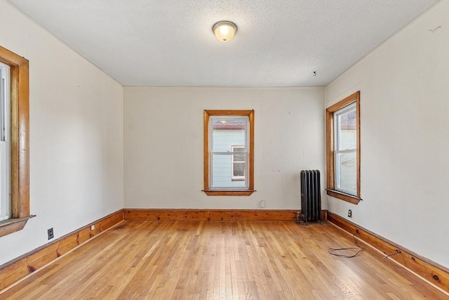 unfurnished room featuring radiator, a textured ceiling, and light wood-type flooring