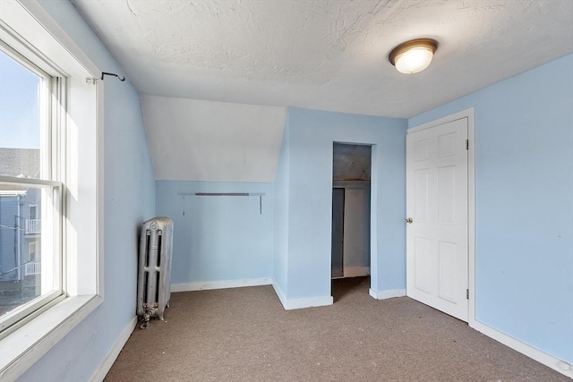 interior space featuring carpet floors, radiator, and a textured ceiling