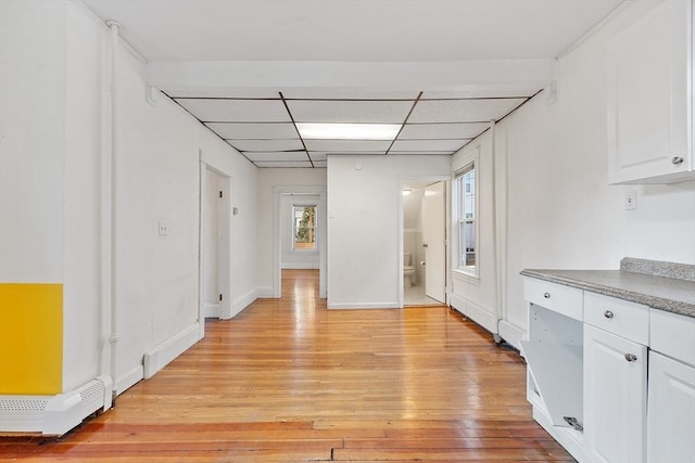 kitchen with white cabinets, a drop ceiling, light hardwood / wood-style floors, and a baseboard heating unit