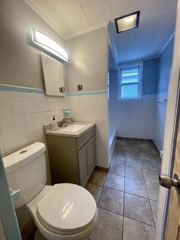 bathroom featuring tile walls, ornamental molding, and a wainscoted wall