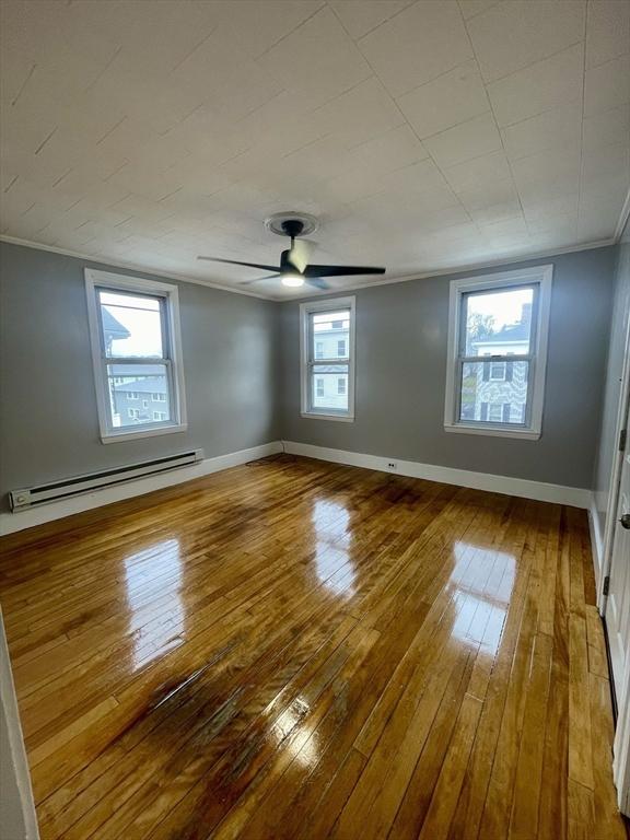 spare room with baseboards, ceiling fan, a baseboard heating unit, and hardwood / wood-style flooring