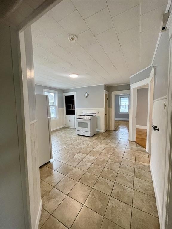 interior space with baseboards, light tile patterned floors, and white appliances