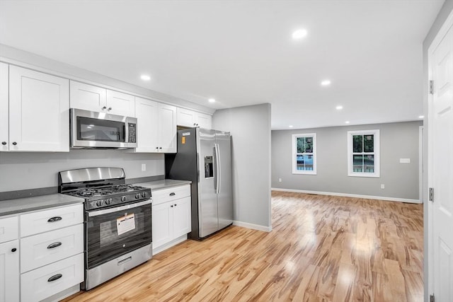 kitchen with white cabinetry, stainless steel appliances, and light hardwood / wood-style floors