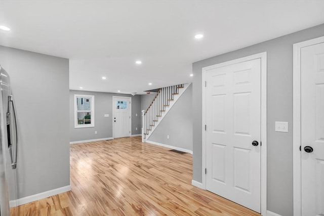 basement featuring stainless steel fridge with ice dispenser and light wood-type flooring