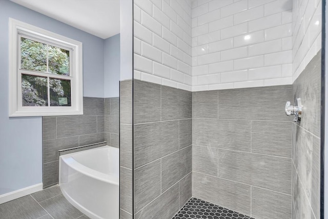 bathroom with tile walls, tile patterned floors, and separate shower and tub