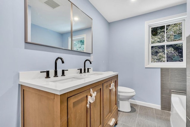 bathroom with vanity, tile patterned flooring, a tub, and toilet