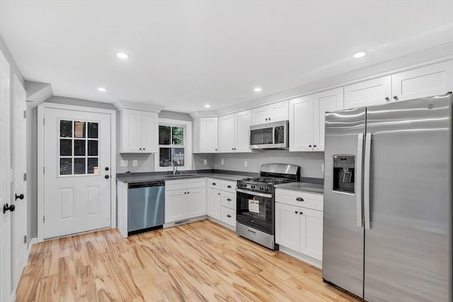 kitchen with stainless steel appliances, sink, light hardwood / wood-style flooring, and white cabinets