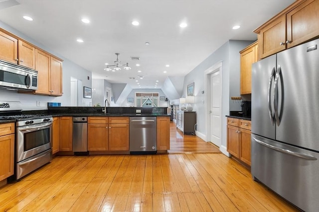 kitchen with stainless steel appliances, a chandelier, a peninsula, light wood finished floors, and a sink
