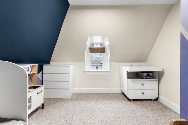 carpeted bedroom featuring lofted ceiling, baseboards, and a sink