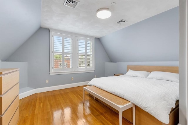 bedroom featuring light wood-style flooring, vaulted ceiling, and baseboards
