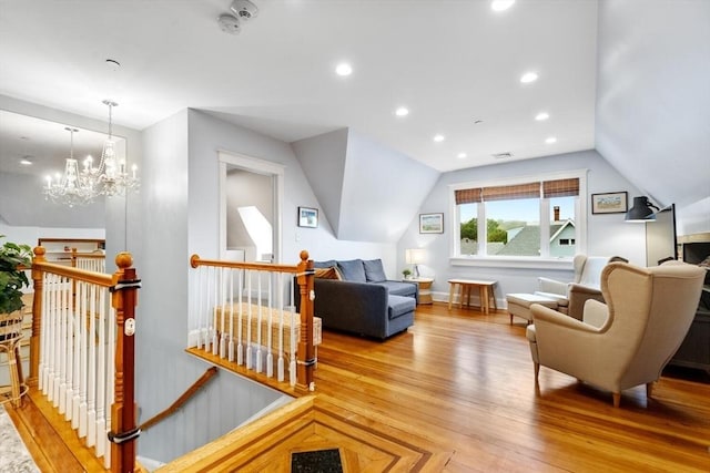 living area with an upstairs landing, vaulted ceiling, light wood finished floors, recessed lighting, and a chandelier