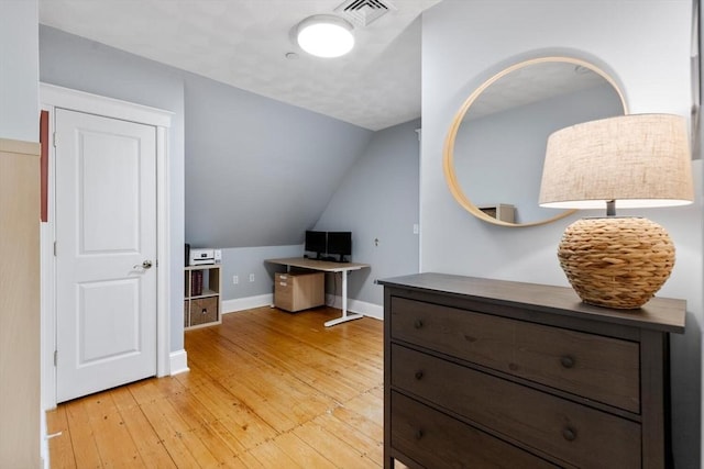 office area featuring light wood finished floors, vaulted ceiling, and baseboards