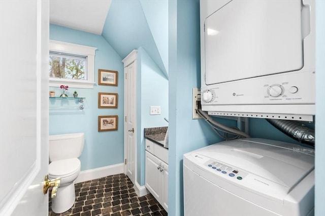 washroom with stacked washer / drying machine and baseboards