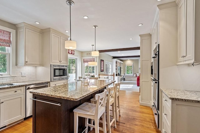 74 Charter Rd, Acton, MA 01720 - kitchen featuring stainless steel appliances, a kitchen island, light wood-style flooring, tasteful backsplash, and light stone counters