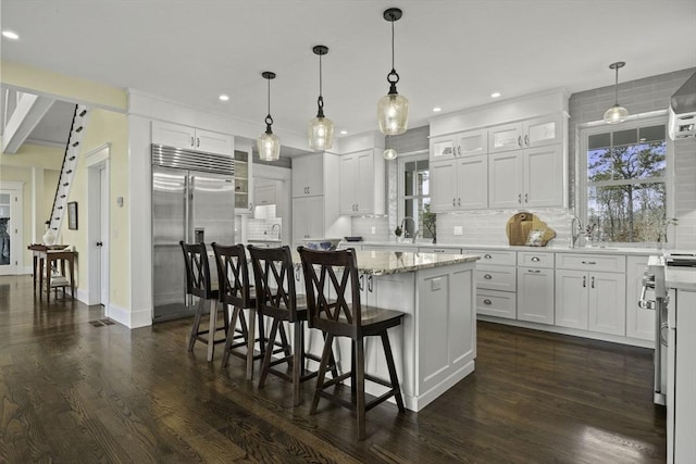 kitchen with decorative light fixtures, a center island, white cabinets, and appliances with stainless steel finishes