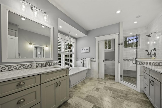 bathroom with shower with separate bathtub, tile walls, and vanity