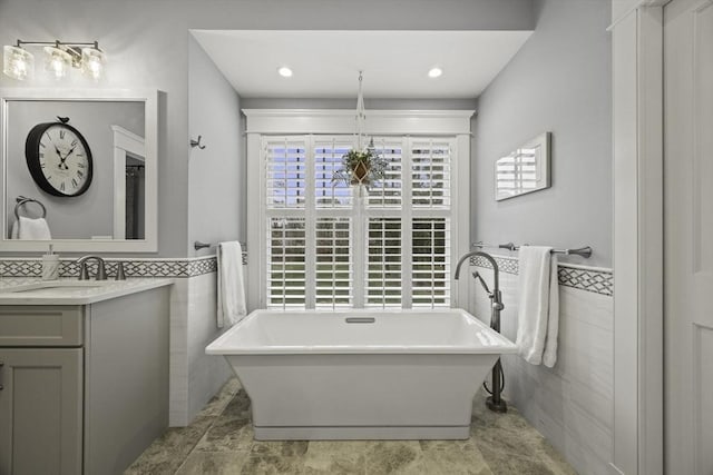 bathroom featuring vanity, a bathing tub, and tile walls