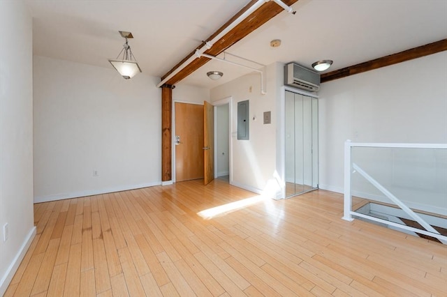 spare room with baseboards, wood finished floors, electric panel, and beam ceiling