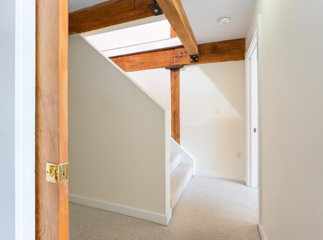 stairs featuring carpet floors, beam ceiling, and baseboards
