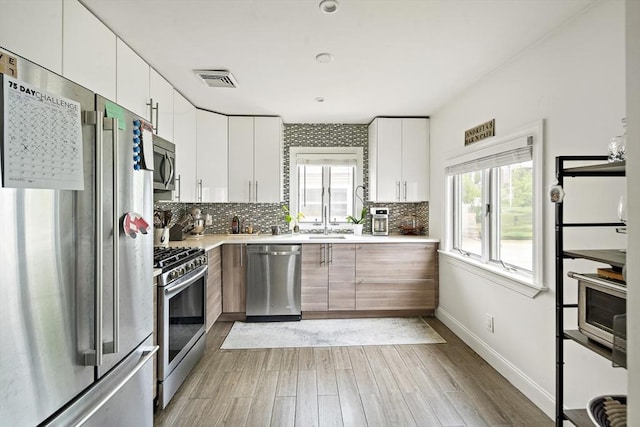 50 Triton Ave, Winthrop, MA 02152 - kitchen featuring appliances with stainless steel finishes, light countertops, light wood finished floors, tasteful backsplash, and a sink