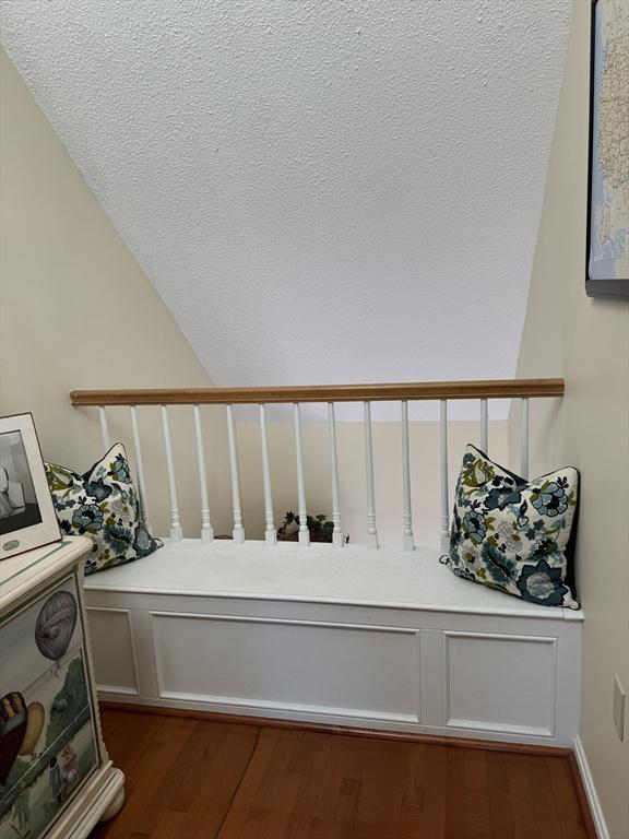 staircase with wood finished floors and a textured ceiling