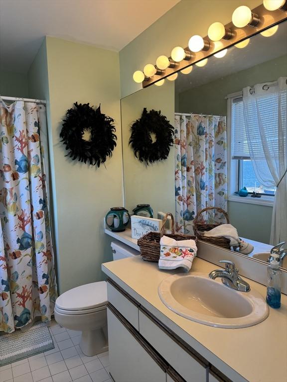bathroom featuring tile patterned floors, vanity, toilet, and curtained shower