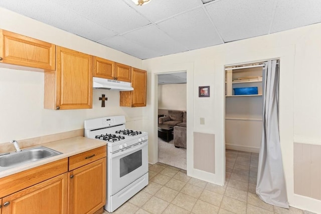 342 Broadway, North Attleboro, MA 02760 - kitchen featuring white range with gas stovetop, under cabinet range hood, a paneled ceiling, light countertops, and light floors