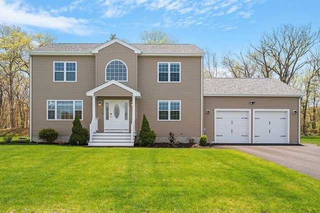 colonial house featuring a garage, a front yard, and aphalt driveway