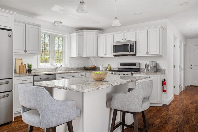 kitchen featuring a kitchen island, a kitchen bar, white cabinets, a sink, and stainless steel appliances