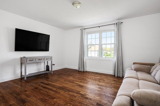 living area with baseboards and dark wood-type flooring