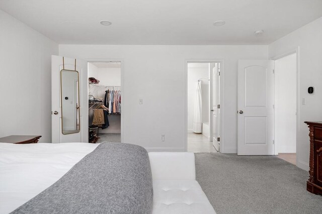 bedroom with carpet flooring, ensuite bath, a walk in closet, and a closet