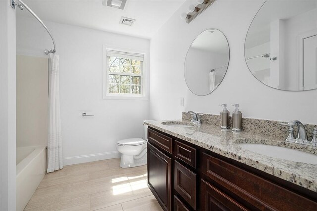 bathroom featuring visible vents, a sink, double vanity, and toilet
