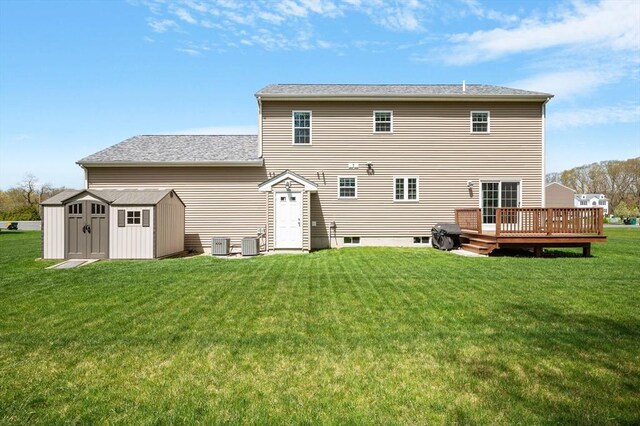 back of property with a storage unit, central AC, a deck, an outbuilding, and a yard