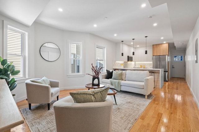 living room with light wood-style floors, recessed lighting, and baseboards