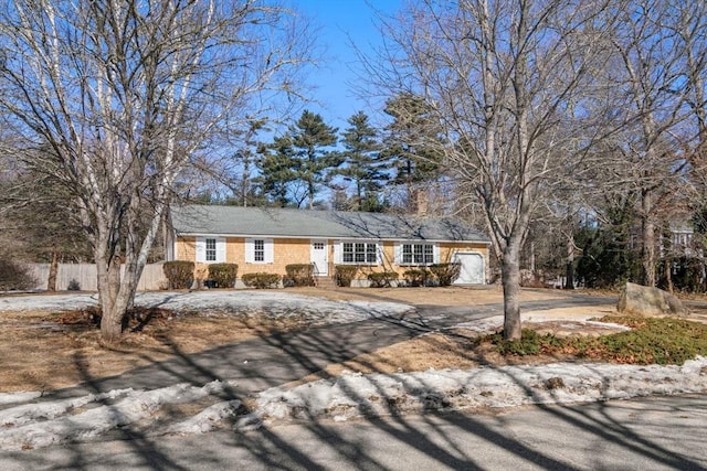 view of front of home featuring driveway, a garage, and fence