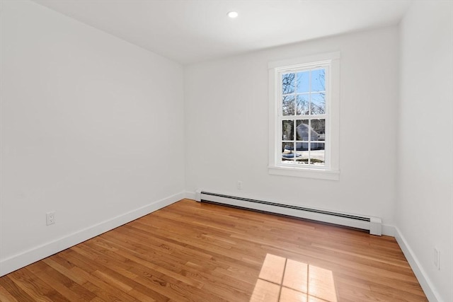 empty room featuring baseboards, light wood finished floors, and baseboard heating