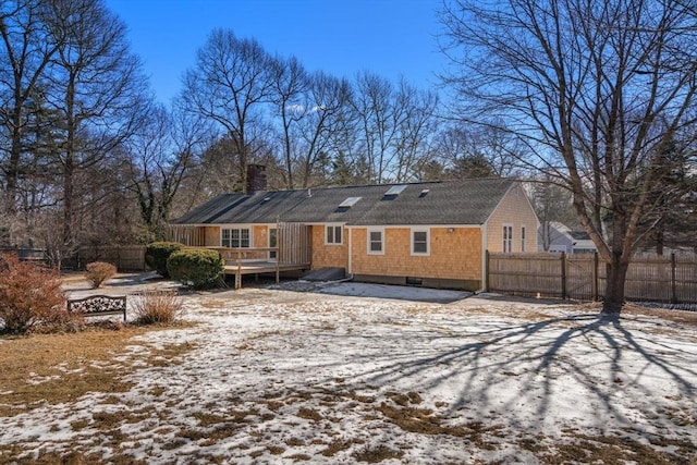 snow covered property with a chimney, fence, and a wooden deck